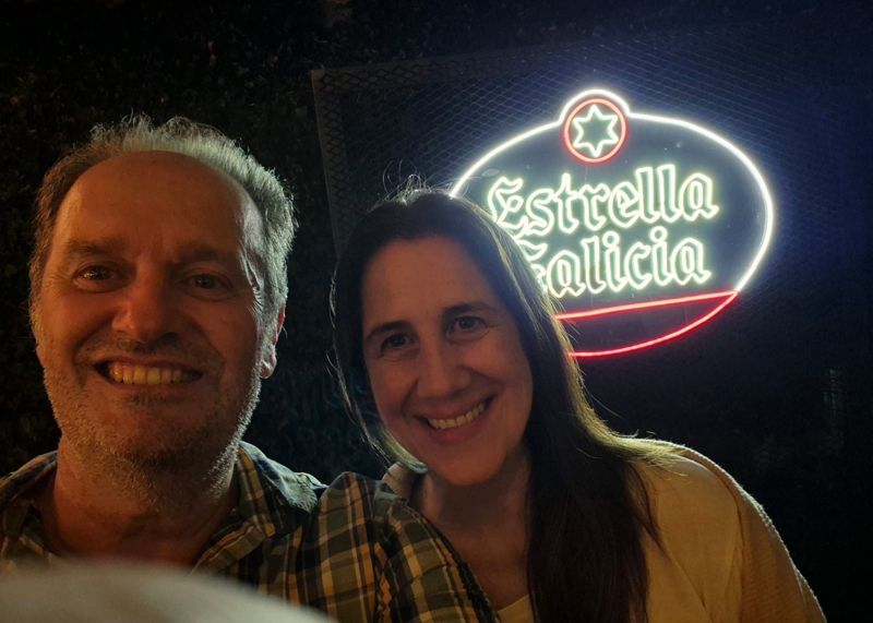 Dos invitados sonriendo frente al cartel de Estrella Galicia