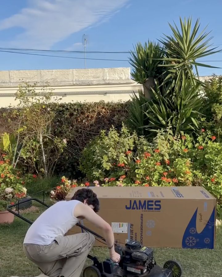 Tomás arreglando el motor de la cortadora al lado de la caja de cartón