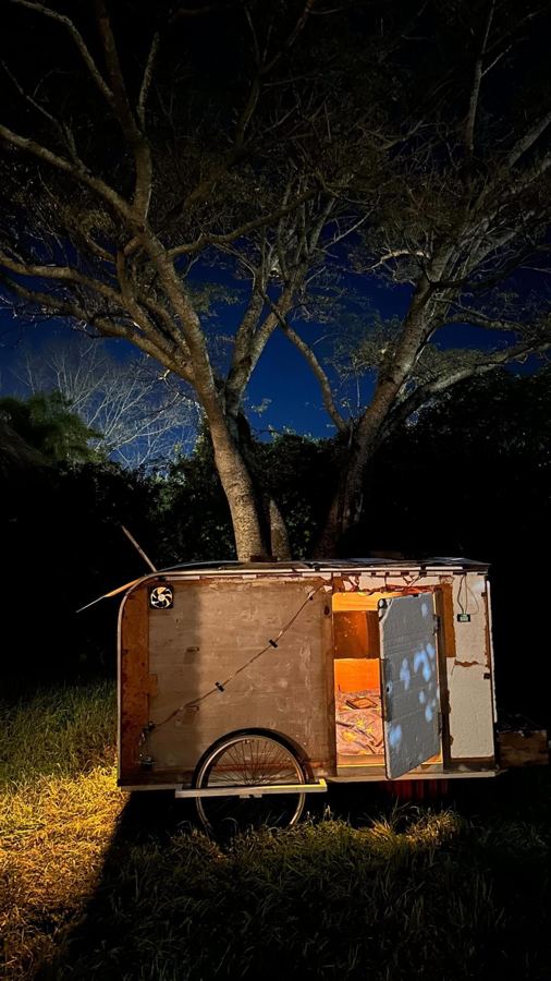 La Bicicasa de noche bajo un árbol, con la puerta abierta y la luz prendida